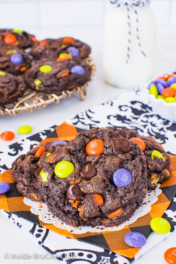 An orange napkin on a white background with chocolate cookies and cream cookies with Halloween candies in them