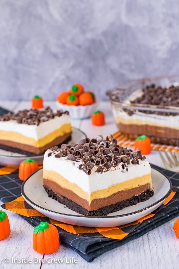 Two plates with pieces of chocolate pumpkin lasagna topped with chocolate curls on them