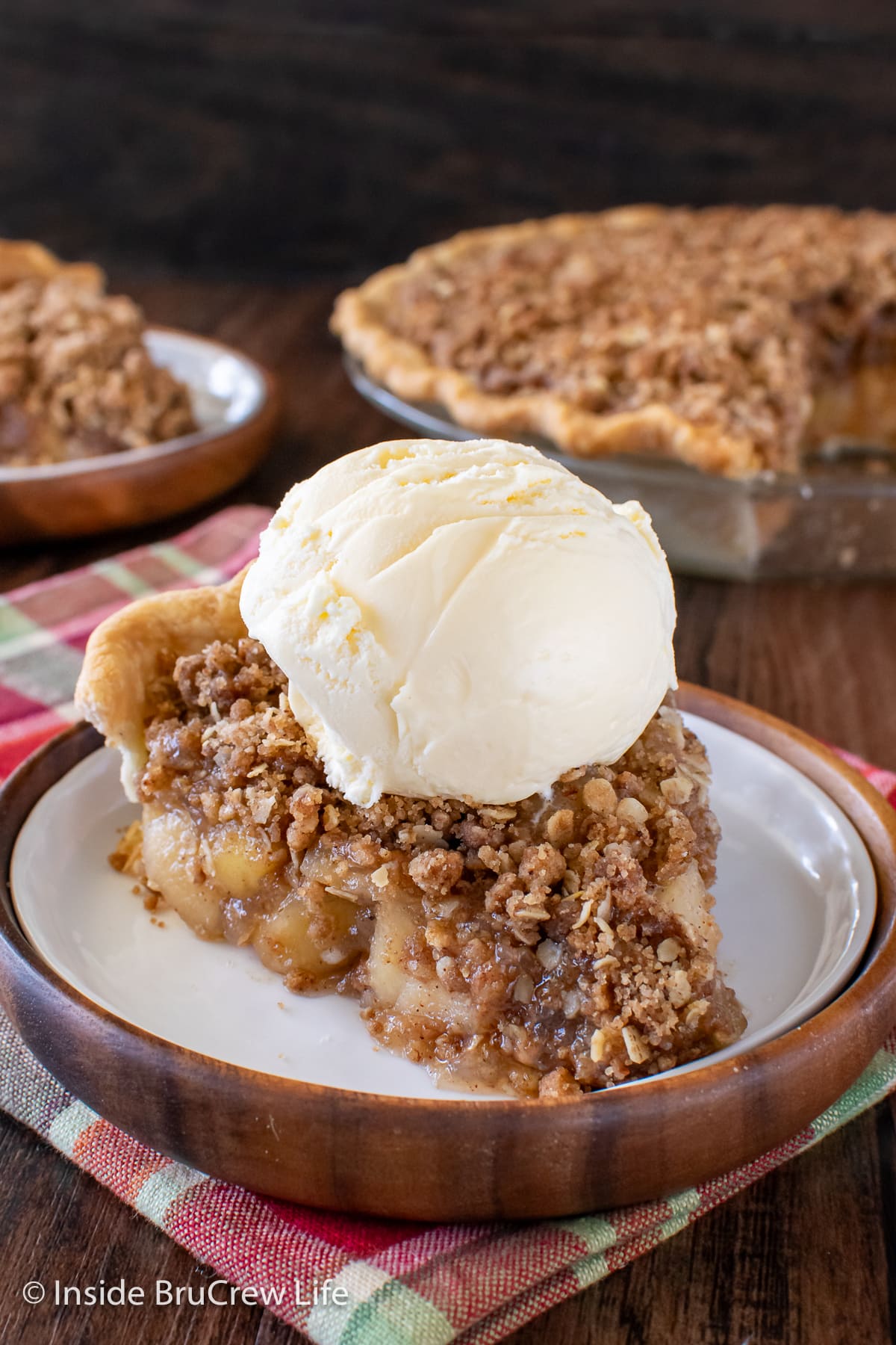 A slice of crumble pie topped with ice cream.