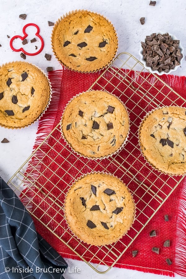 Overhead picture of five cookies on a wire rack with chocolate chunks scattered around.