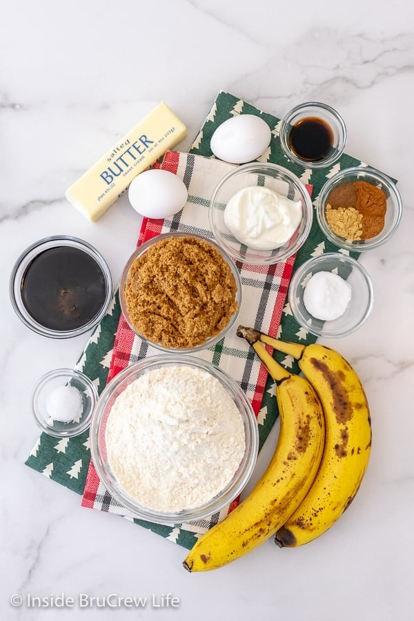 A white background with bowls of ingredients to make gingerbread banana bread.