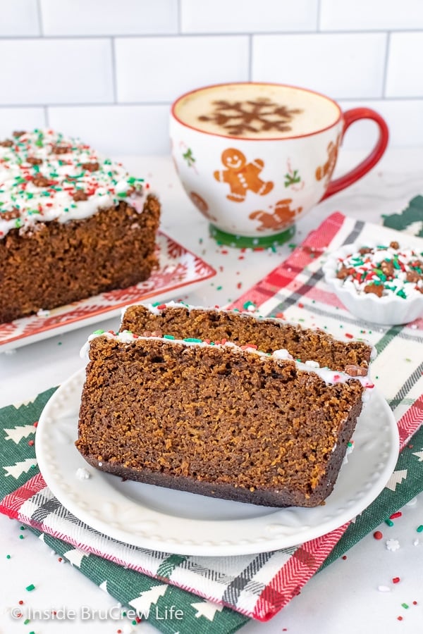 A white plate with two slices of banana bread with glaze and sprinkles on it and a cup of coffee.