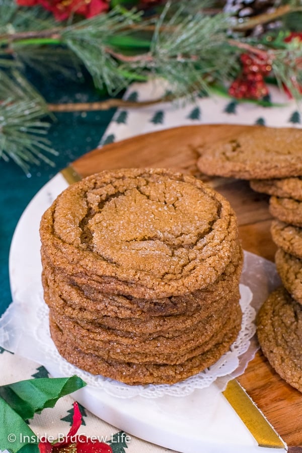 A stack of molasses crackle cookies on a wood tray with more cookies beside the stack