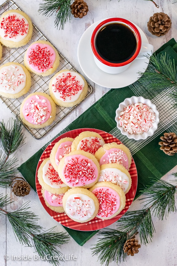 Overhead picture of a red plate and a wire rack with cookies frosted with glaze and candies.
