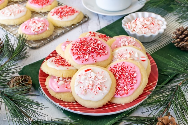 A red plate on a green towel with a stack of cookies coated with pink and white glaze and candies.