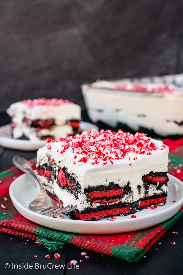 Two white plates with squares of peppermint oreo icebox cake topped with peppermint candies on top