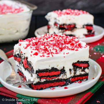 Two white plates with squares of peppermint oreo icebox cake topped with crushed peppermint candies