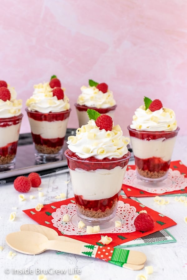 A white and pink board with raspberry white chocolate cheesecake parfaits on it