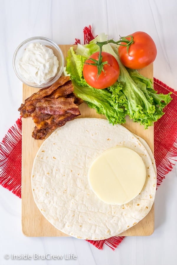 Overhead picture of a cutting board with ingredients to make a BLt tortilla wrap hack on it
