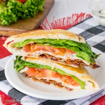 A white plate with two halves of a blt tortilla wrap hack stacked on top of it showing the fillings