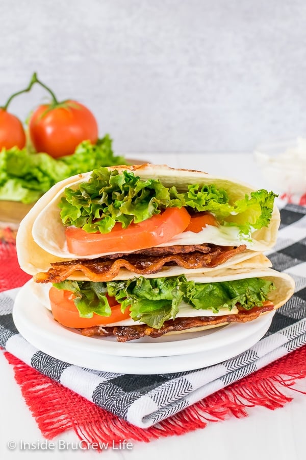 Two BLT tortilla wraps cooked and stacked on top of each other on a white plate