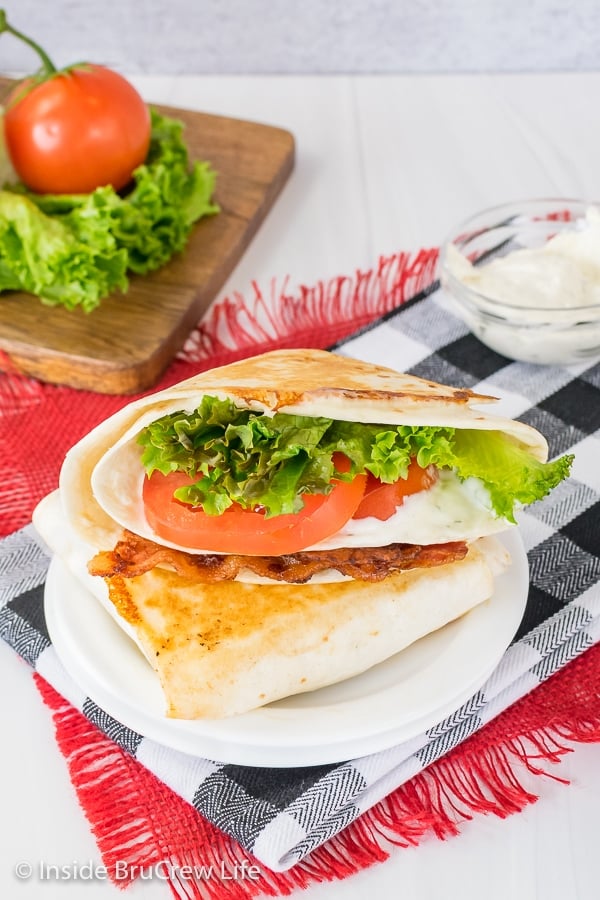 Two BLT tortilla wrap hacks stacked on top of each other on a white plate