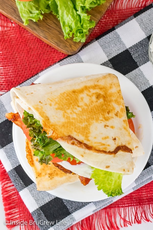 Overhead picture of a white plate with a pan fried BLT tortilla wrap on it