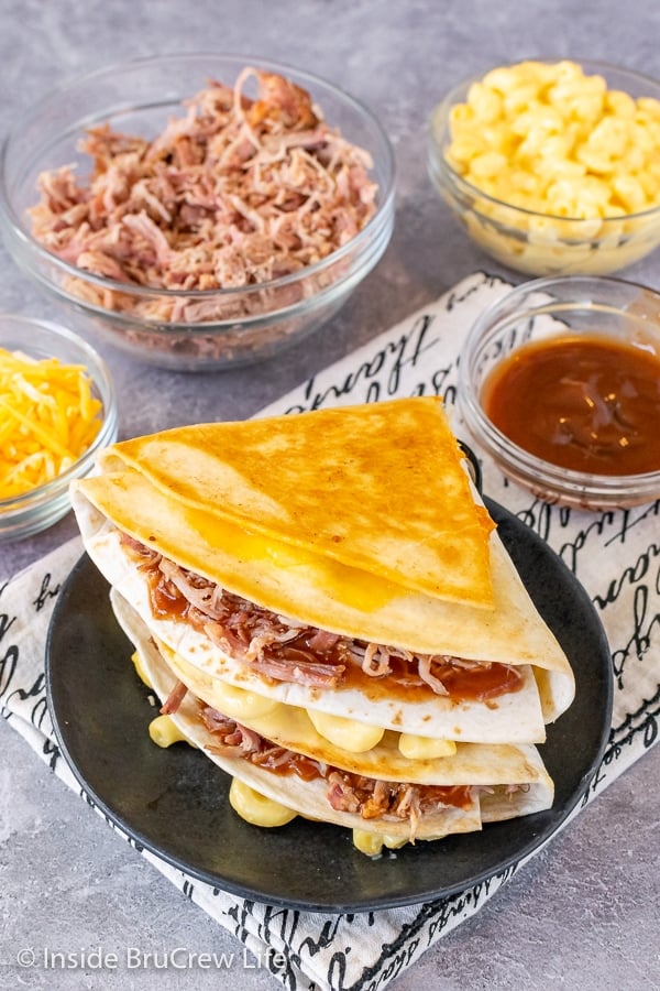 Overhead picture of a black plate with two pulled pork macaroni and cheese tortilla wraps stacked on it