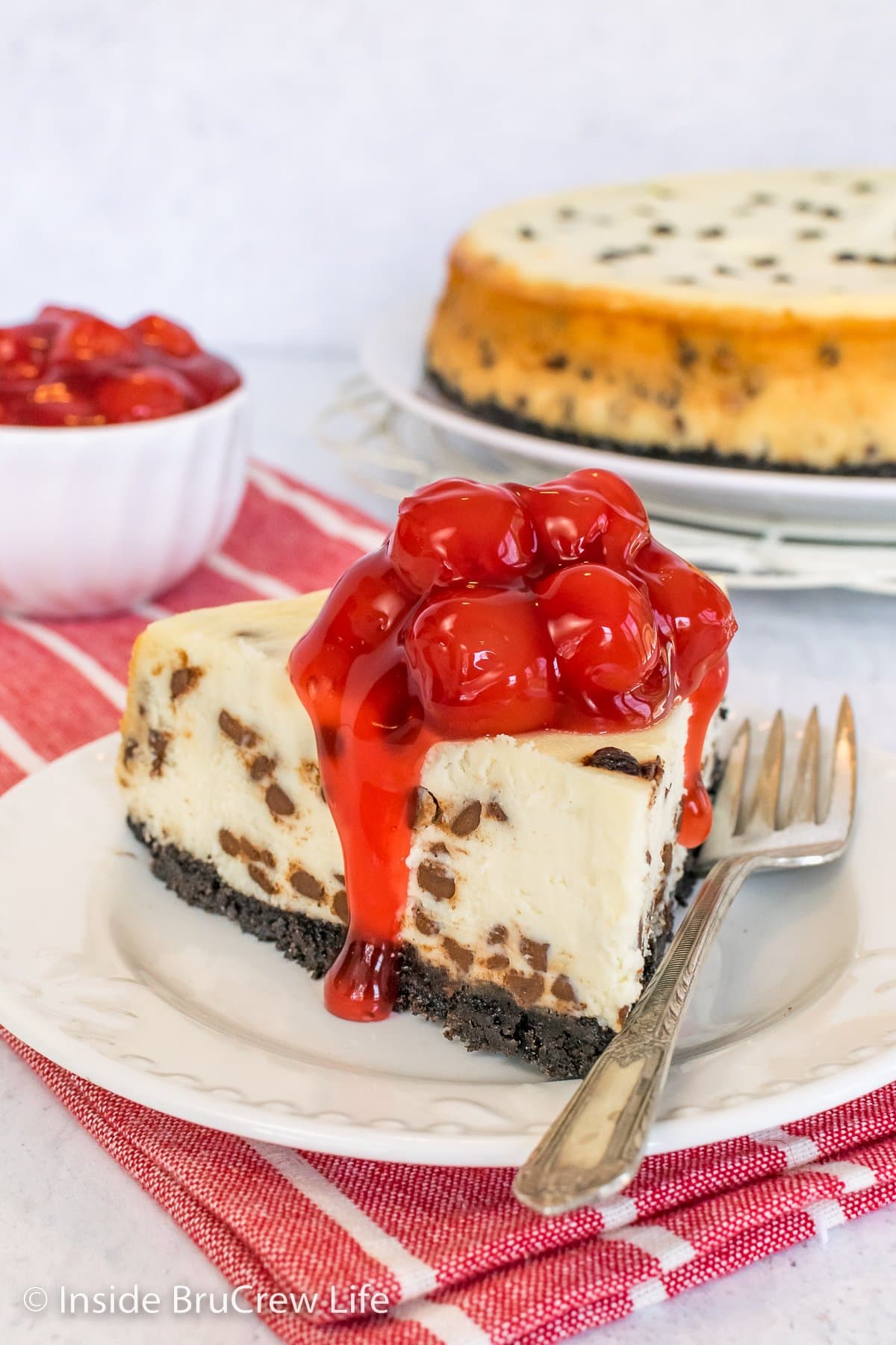 A slice of cheesecake topped with cherry pie filling.