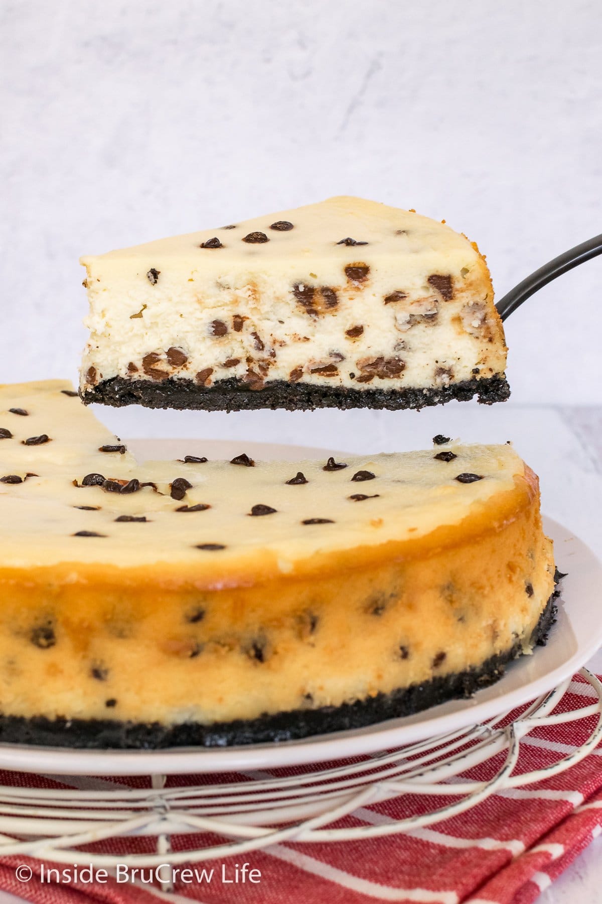 A full sized chocolate chip cheesecake with a slice lifted up.