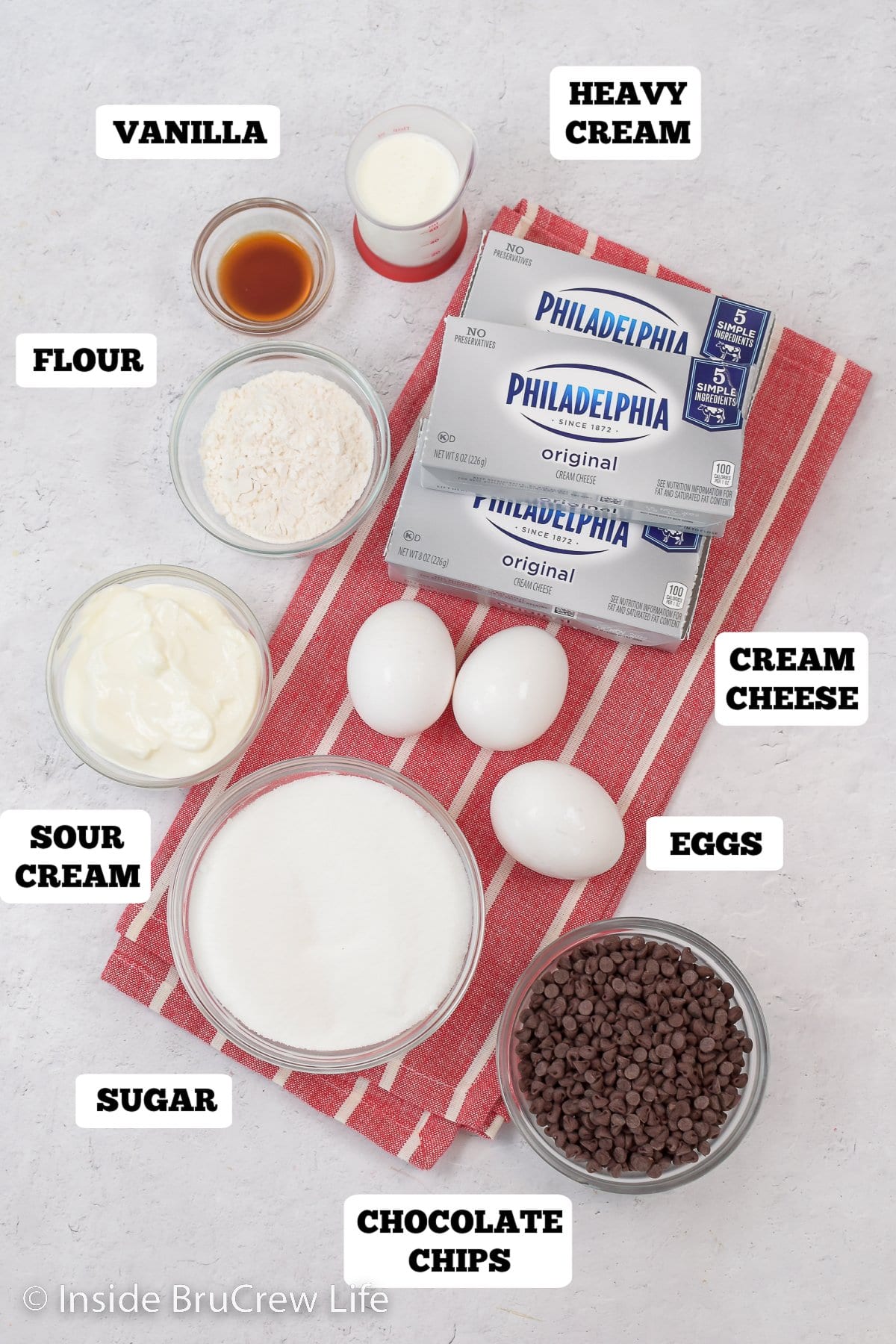 A white board with bowls of ingredients to make cheesecake.