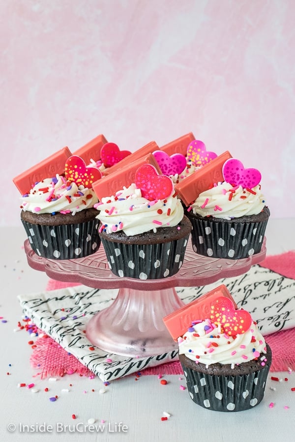 Dark Chocolate Raspberry Filled Cupcakes with frosting, sprinkles, and candies on a pink cake plate