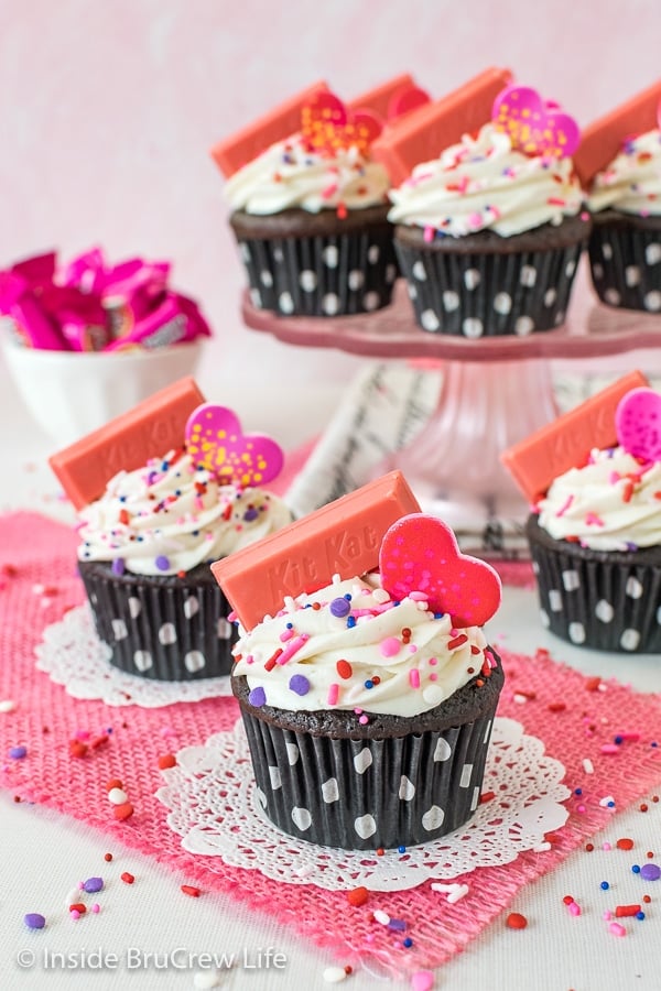 Dark Chocolate Raspberry Cupcakes with vanilla buttercream and sprinkles on a pink towel and cake plate