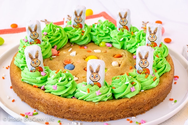 A full cookie cake decorated with green frosting, candy, and Easter bunnies.