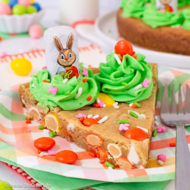 A slice of cookie cake on a plate with a fork.