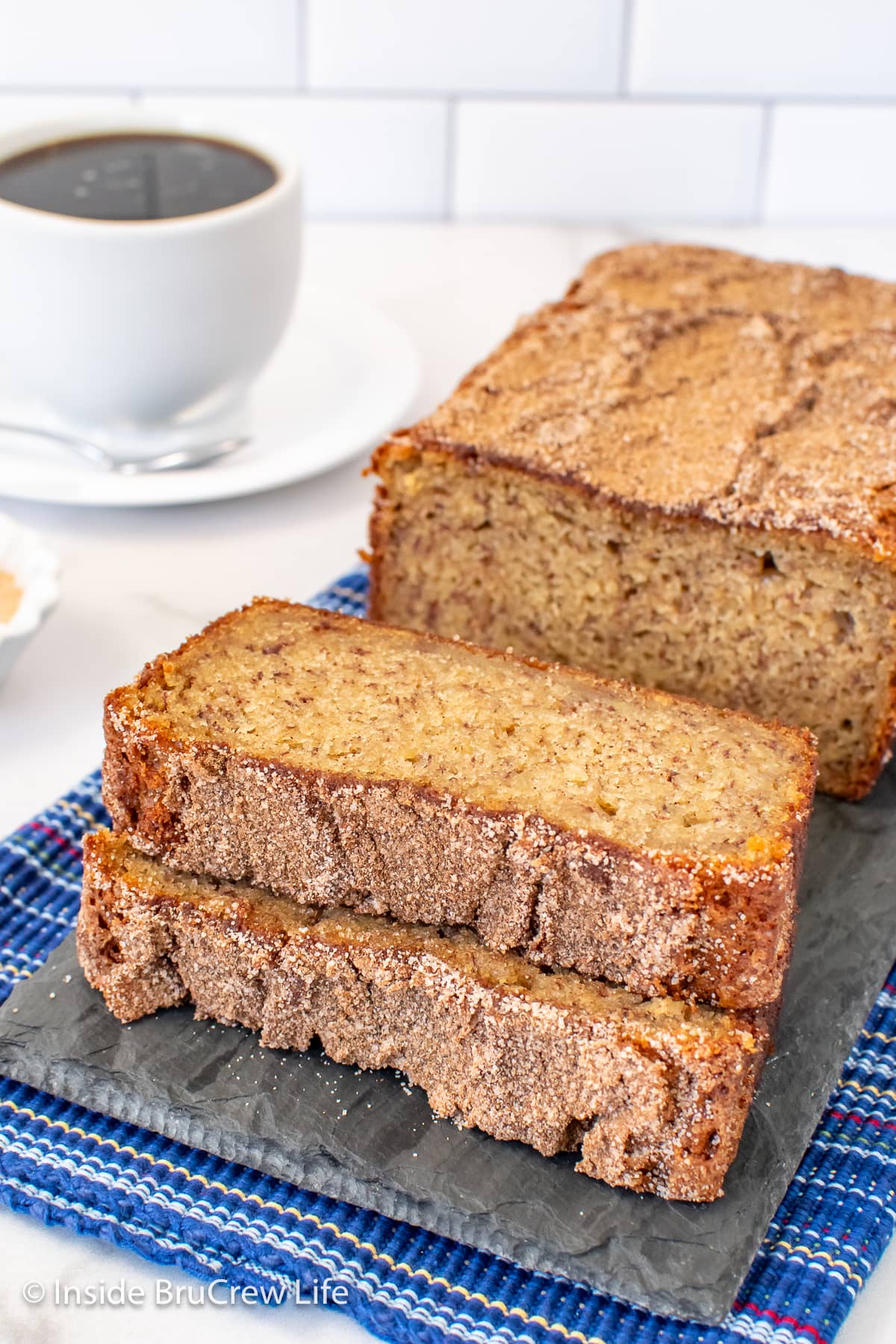 A loaf of quick bread with two slices in front.