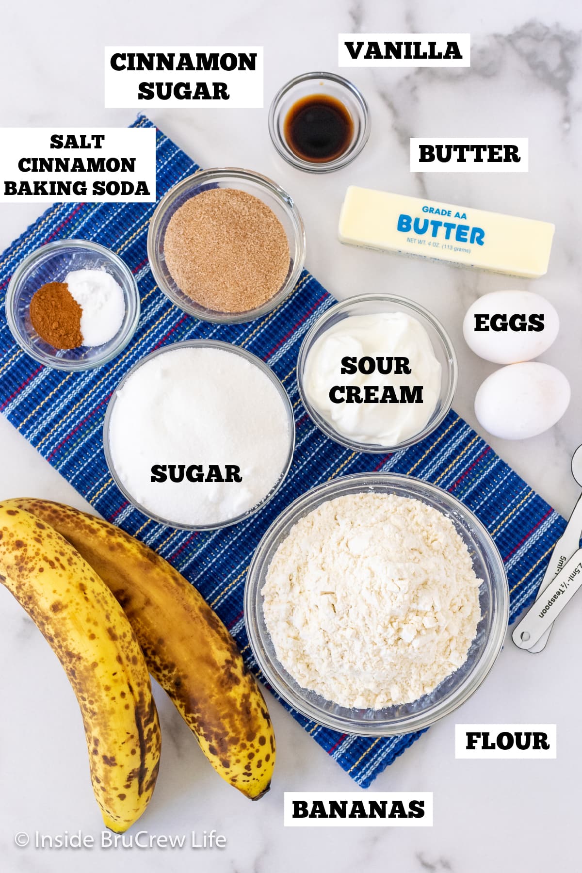 A white board with bowls of ingredients needed to make banana bread.