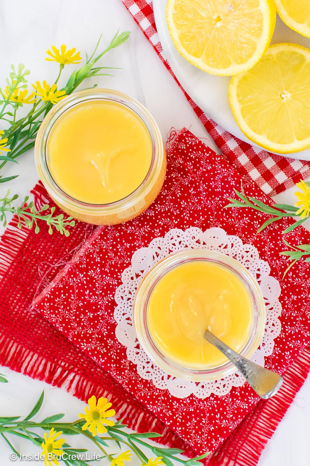 An overhead picture of jars of lemon curd on a red towel.