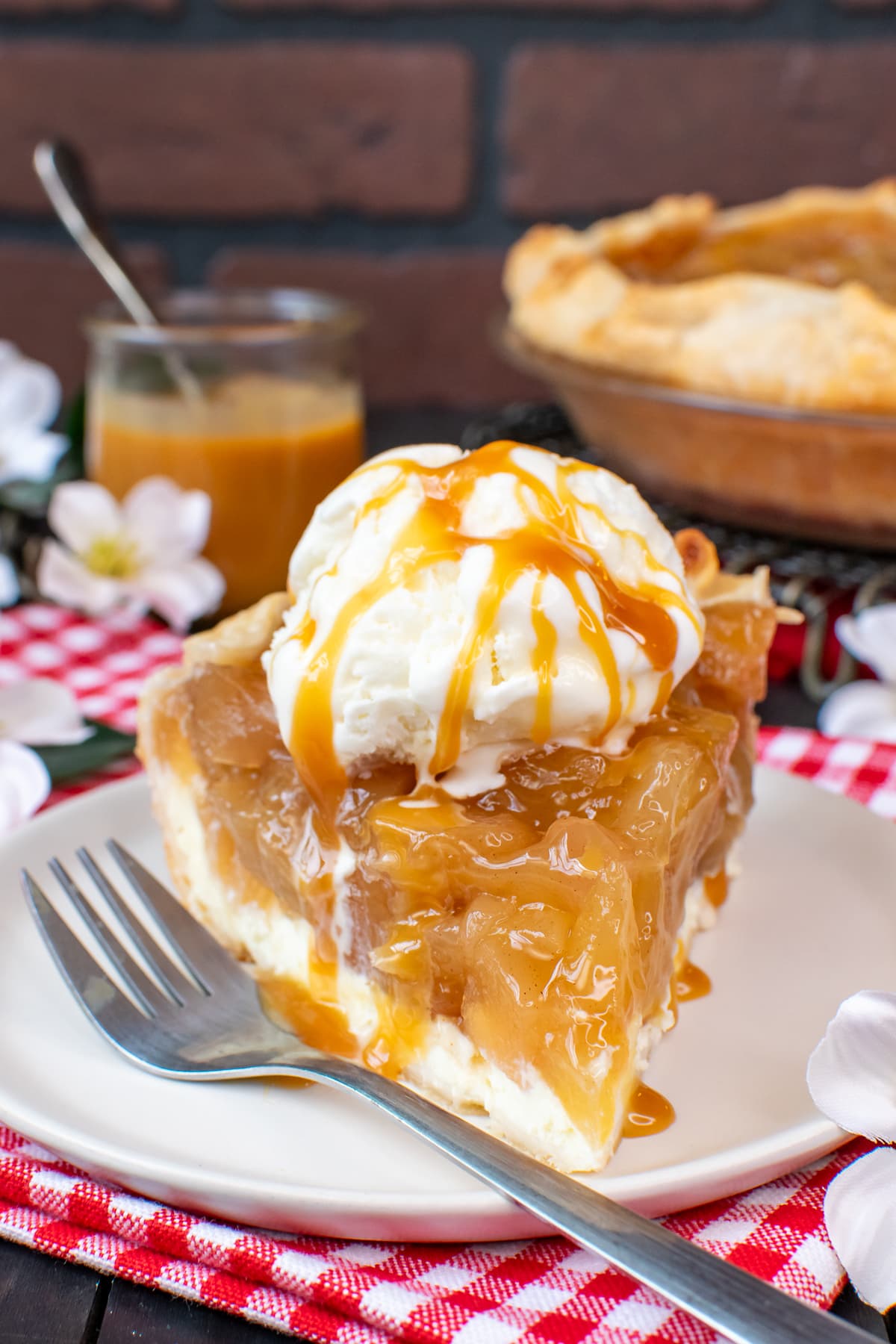 A plate with a slice of pie topped with ice cream and caramel.