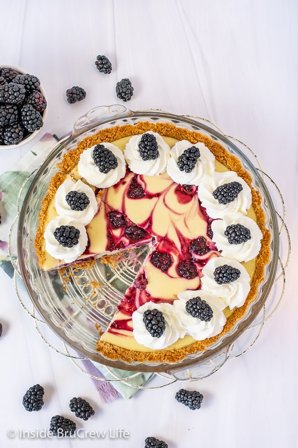 Overhead picture of the of a swirled blackberry cheesecake pie with whipped cream and fresh berries