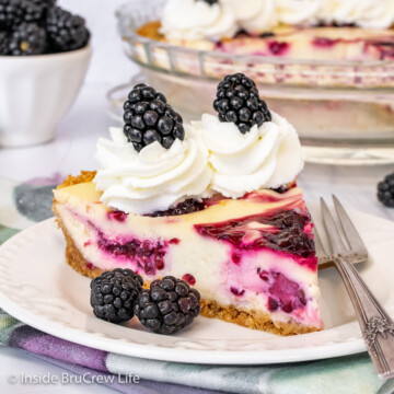 A slice of blackberry cheesecake pie topped with whipped cream and blackberries on a white plate