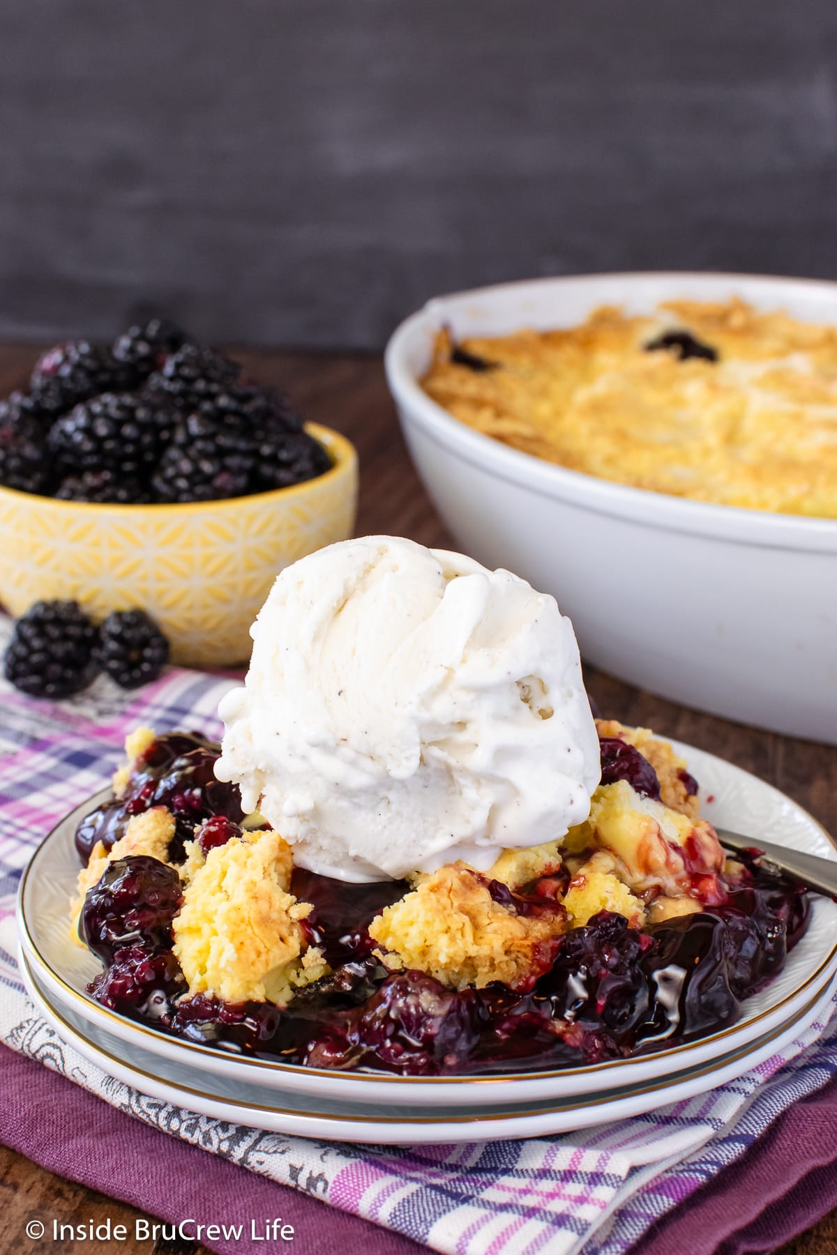 A scoop of fruit cobbler on a plate with ice cream.