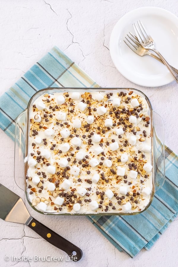 Overhead picture of a pan of chocolate icebox cake topped with whipped cream, marshmallows, nuts, and chocolate chips.