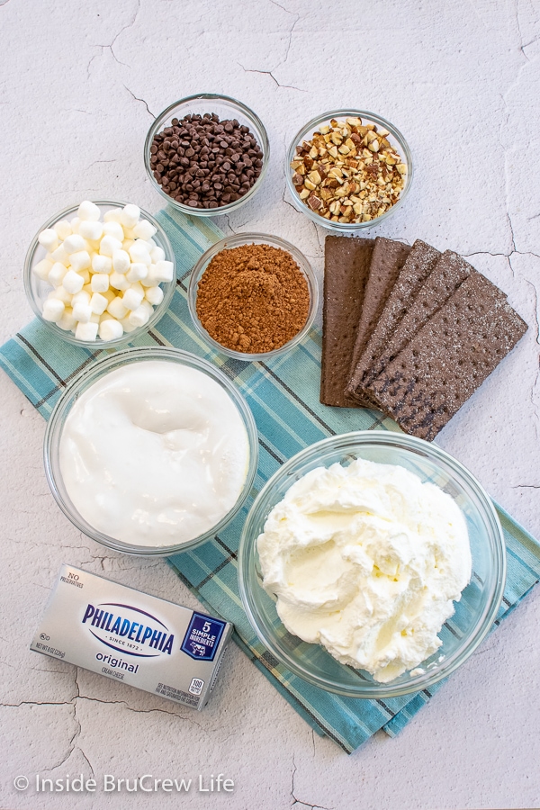 Bowls of ingredients to make a rocky road icebox cake on a white board.