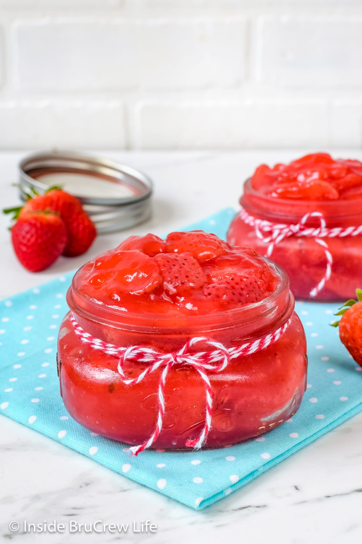 Two small clear jars filled with strawberry pie filling.