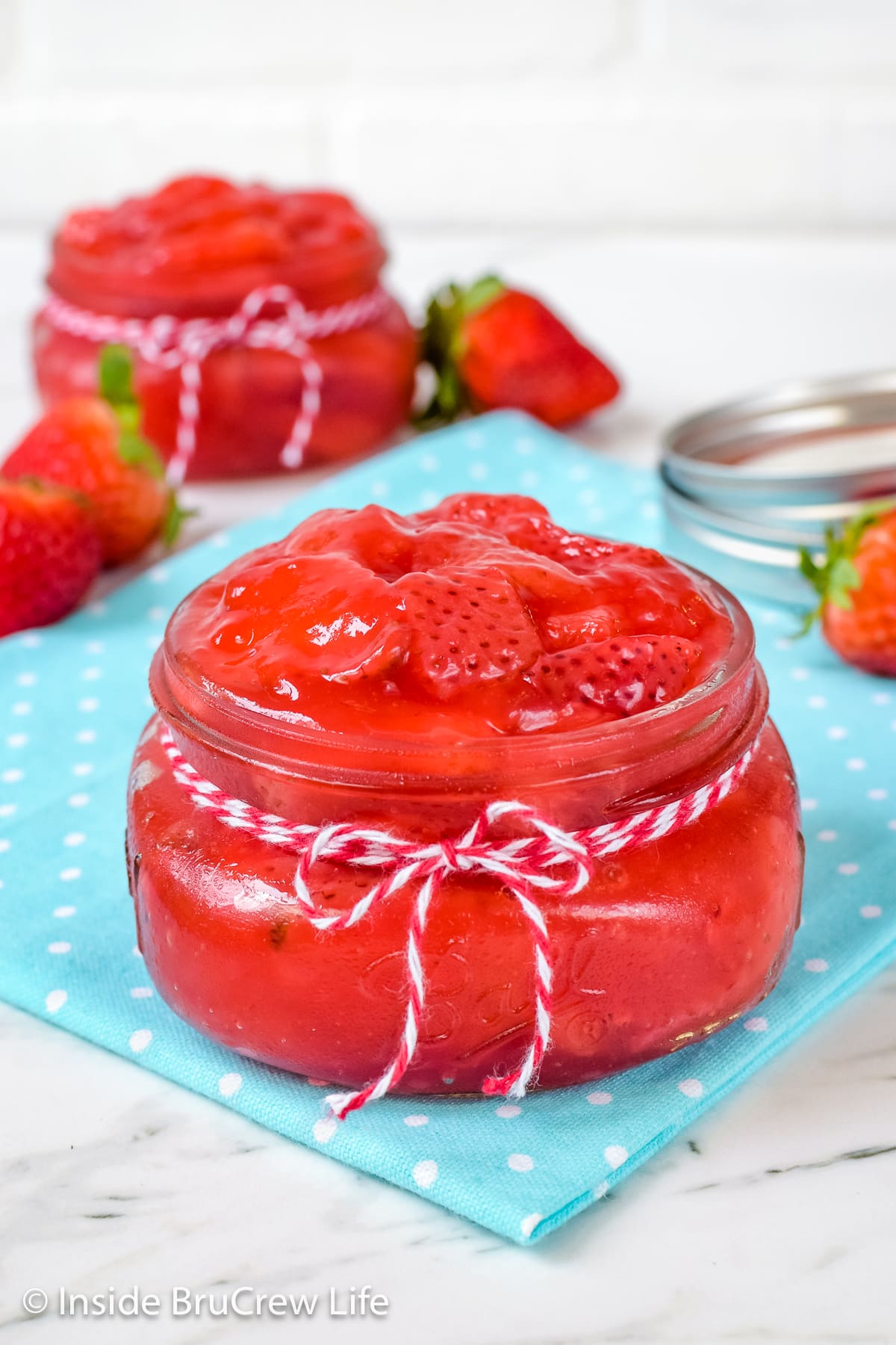 Two small clear jars filled with strawberry pie filling.