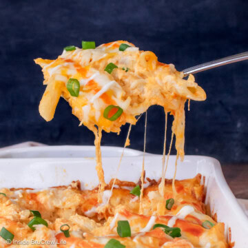 A scoop of cheesy pasta being lifted out of a casserole dish.