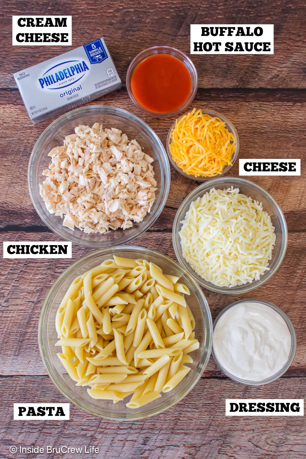 A board with bowls of ingredients needed to make buffalo pasta.