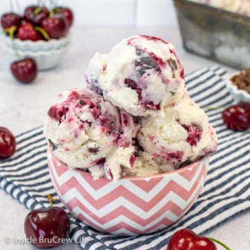 A pink and white bowl with scoops of vanilla ice cream with cherry pie filling swirls.
