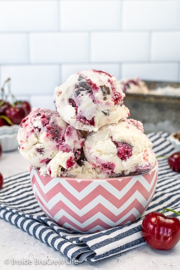 A pink and white bowl filled with scoops of cherry vanilla ice cream.