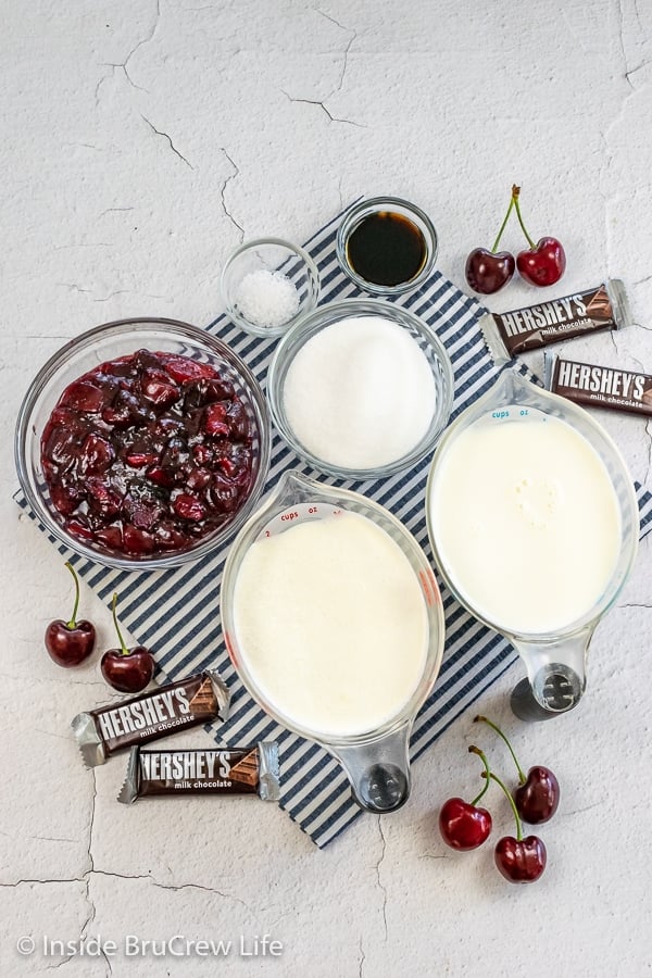 A white board with bowls of ingredients to make a homemade vanilla ice cream with cherry pie filling.