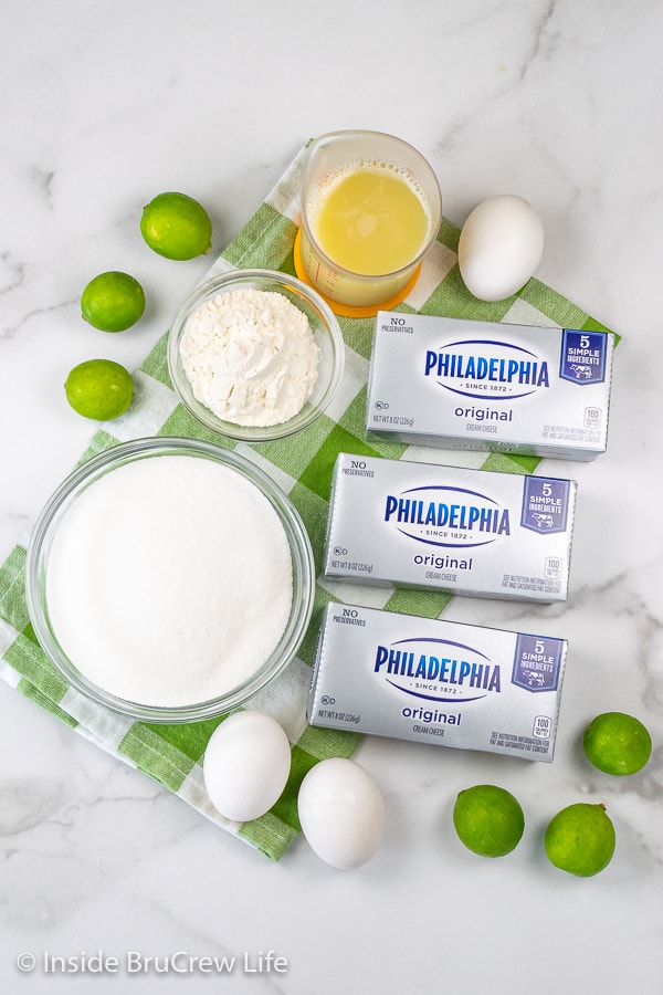 A white board with bowls filled with the ingredients needed to make a full size key lime cheesecake.