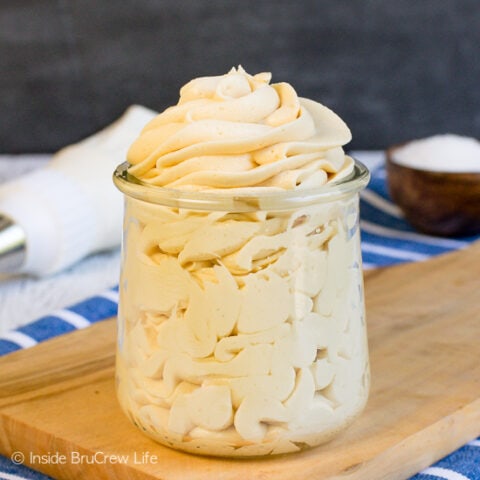 A clear jar filled with a swirl of salted caramel frosting.
