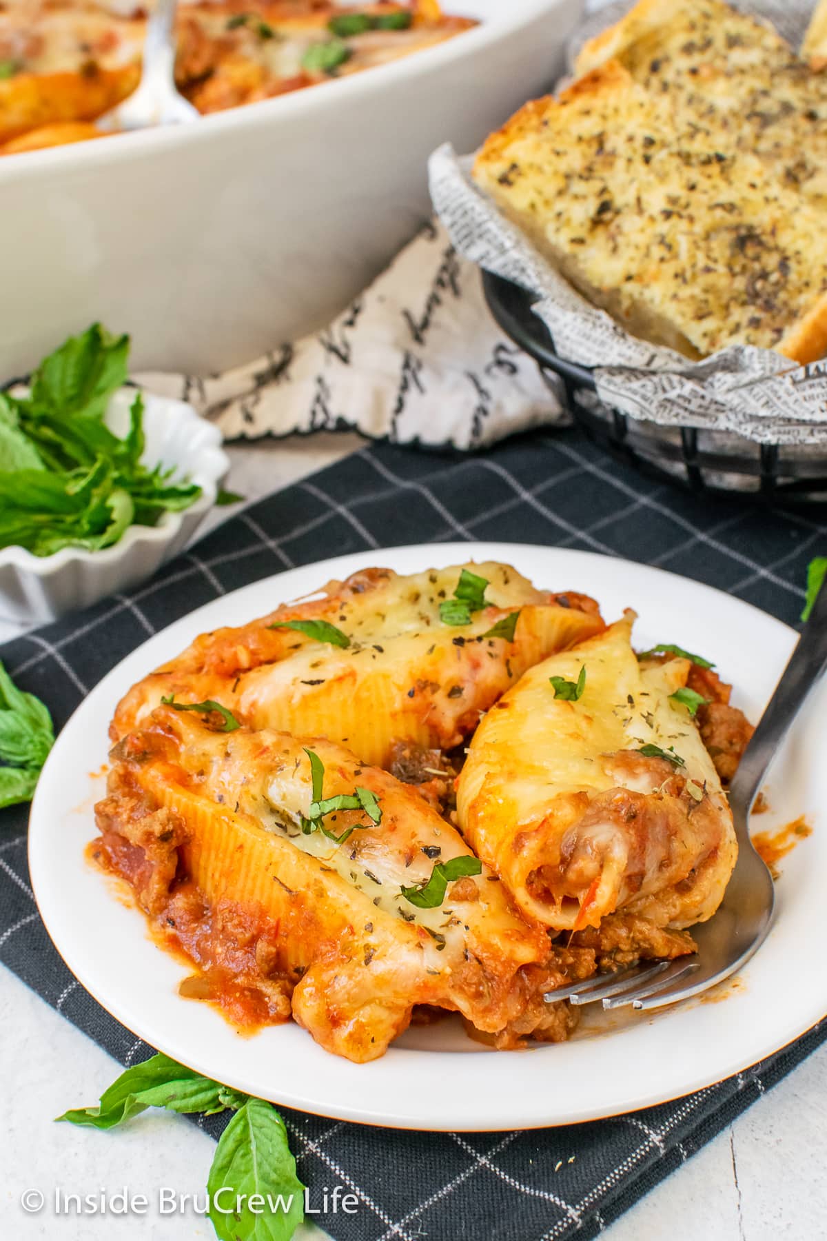 Three cheesy stuffed shells on a white plate.