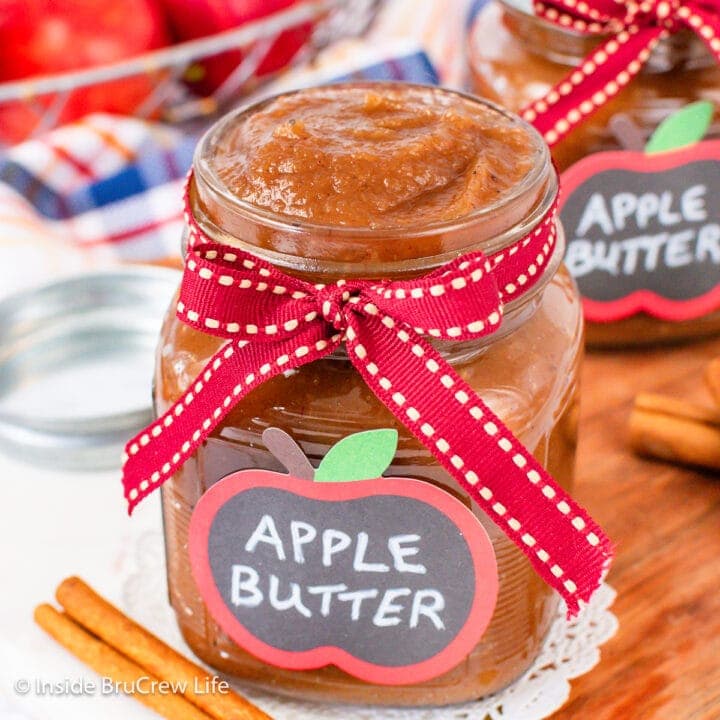 A clear jar with a ribbon filled with apple spread.
