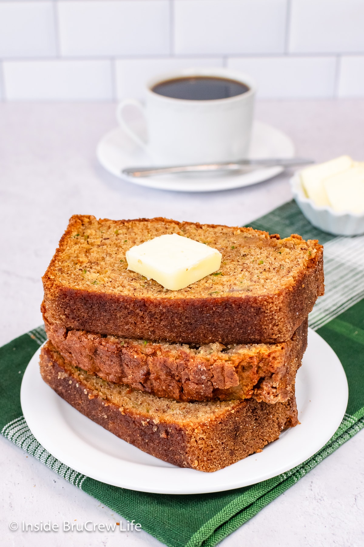 Three slices of zucchini bread stacked on a white plate.
