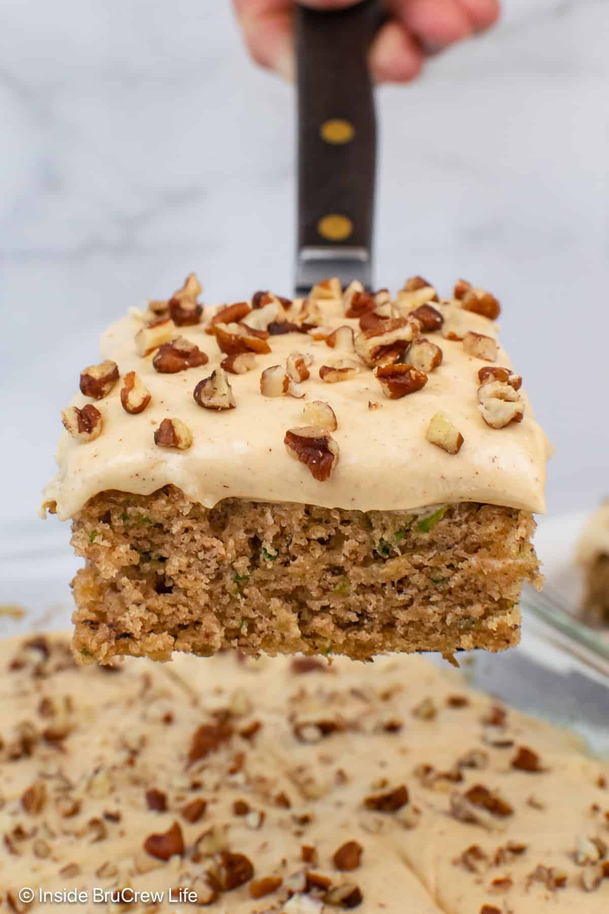 A spatula lifting a piece of banana zucchini cake out of a pan.