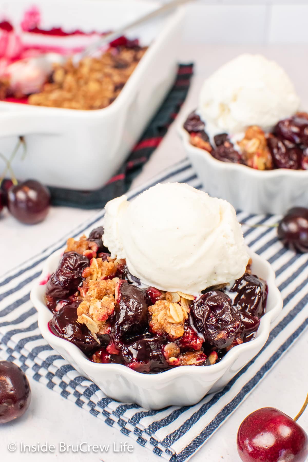 Bowls of cherry oat crumble on a blue striped towel.