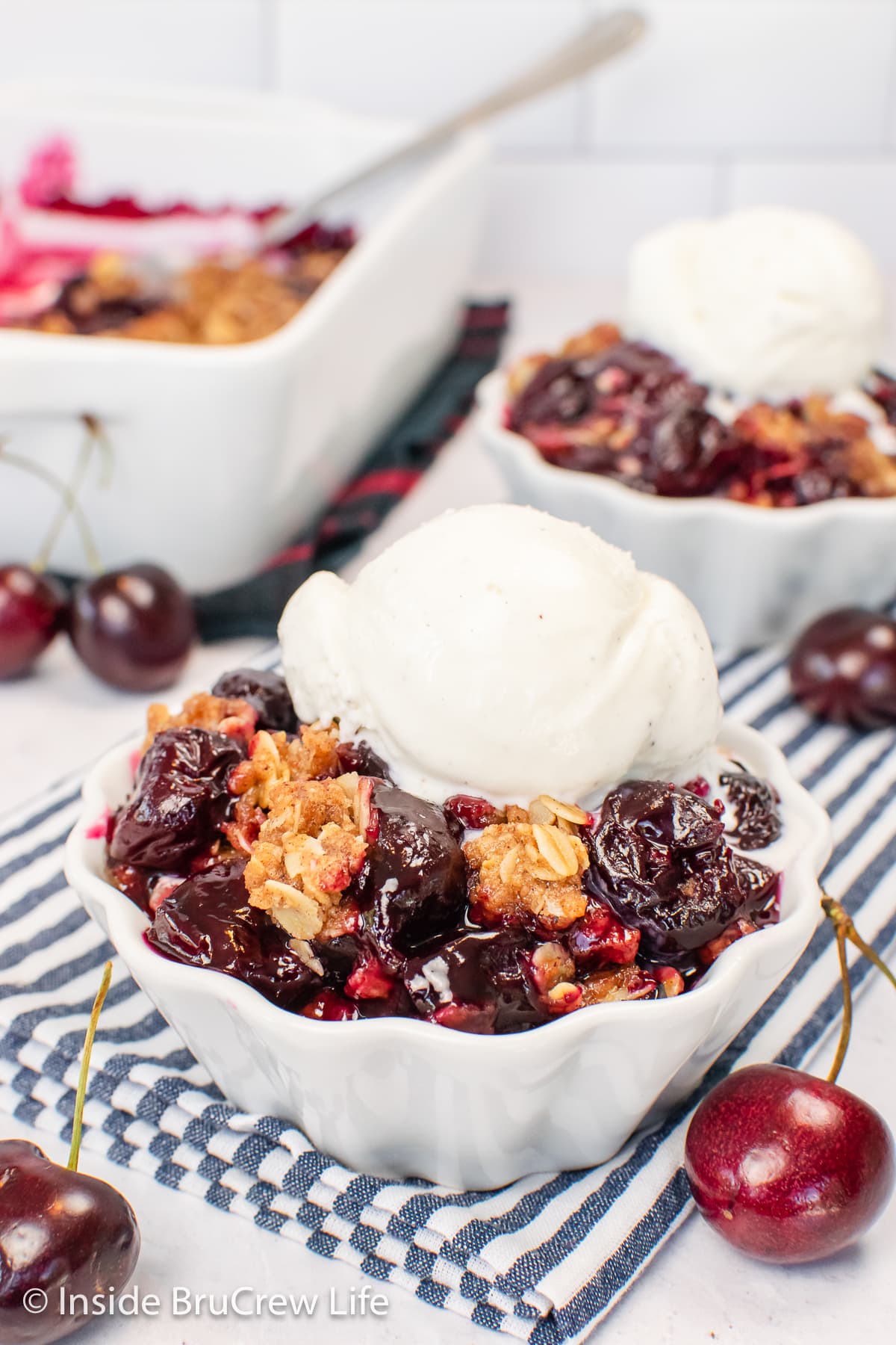 Two white bowls filled with a cherry and oat dessert.