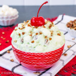 A red bowl filled with green pistachio fluff salad.